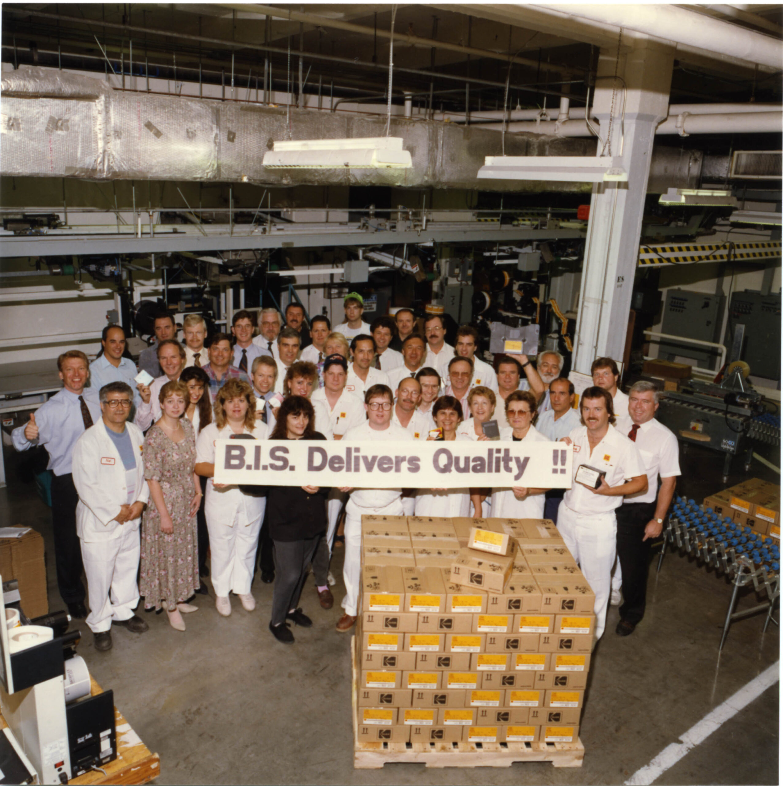Group of individuals from Kodak's Business Imaging Systems (B.I.S.) team holding a banner that says "B.I.S. Delivers Quality"