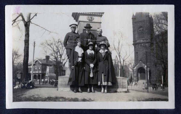A family posed in front of a monument at the corner of Sherbourne and Carlton Streets, with St. Luke's United Church in the background.
