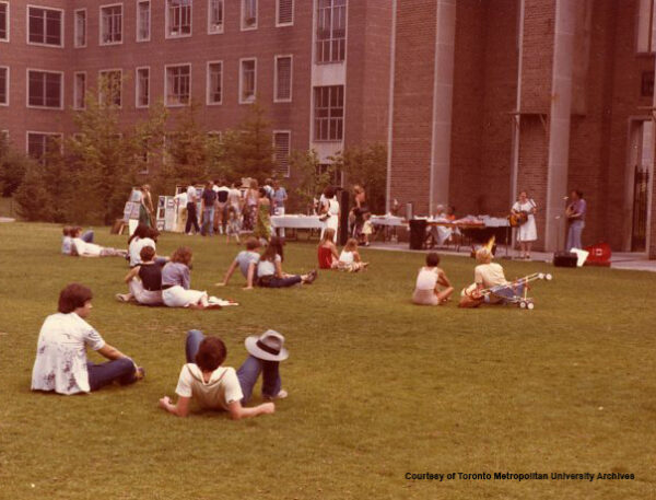 People seated on grass in Kerr Hall Quad listening to music