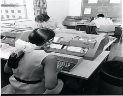 Photo of a woman in the computer centre “batching” punch card instructions to DAISY. (RG 63.72)